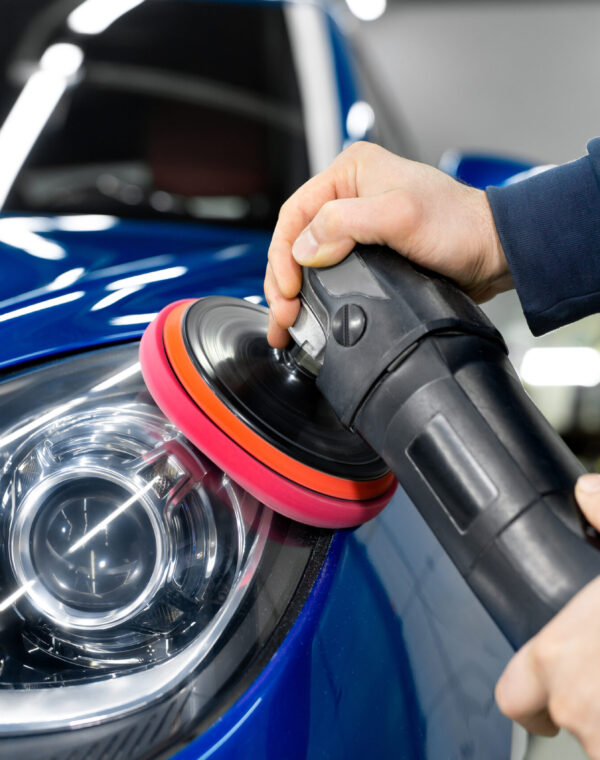 Professional detailing a car in car studio, hands with orbital polisher, scratching remover, vehicle care concept